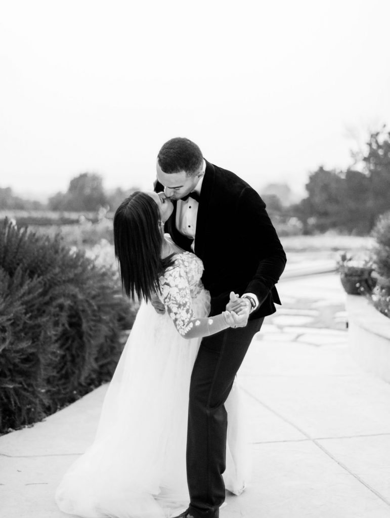 black and white photo of groom dipping bride and kissing her